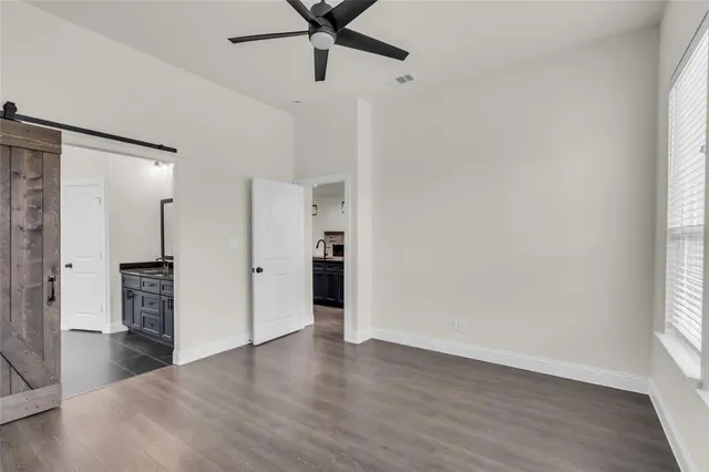 an empty room with wooden floor a ceiling fan and windows