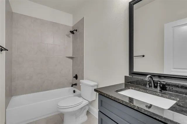 a bathroom with a granite countertop sink a toilet a mirror and shower
