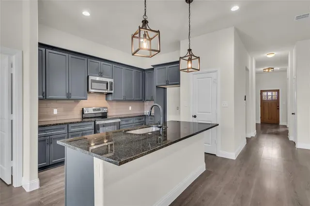 a kitchen with stainless steel appliances granite countertop a sink a stove and a refrigerator