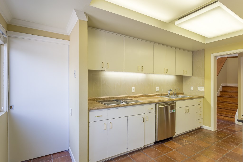 2349 Albans Road, Unit 2 Houston, TX 77005 - Photo 15 of 25 This kitchen features sleek cabinetry with under-cabinet lighting, an integrated cooktop, and a stainless steel dishwasher. It offers ample counter space and a warm, inviting atmosphere, complemented by tile flooring and access to a staircase.