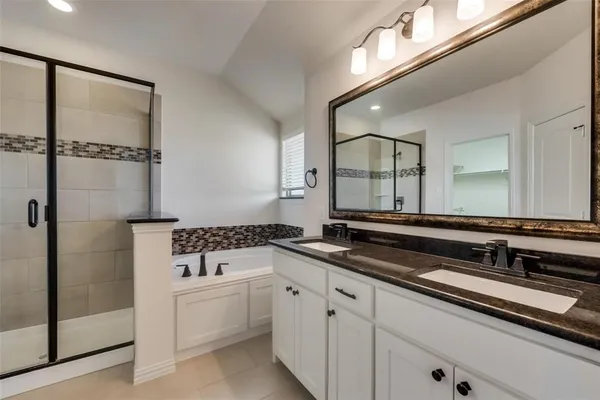 a bathroom with a double vanity sink a mirror and a bathtub