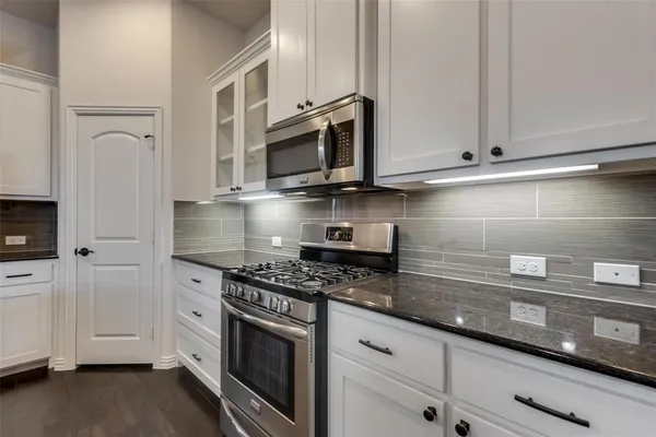 a kitchen with stainless steel appliances granite countertop white cabinets a sink and dishwasher