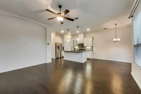 a view of an empty room with kitchen appliances and a ceiling fan