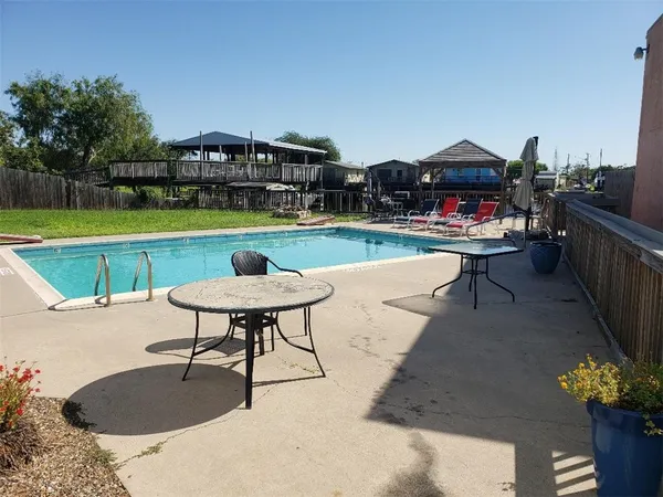 a view of a swimming pool and lounge chairs in back yard of the house