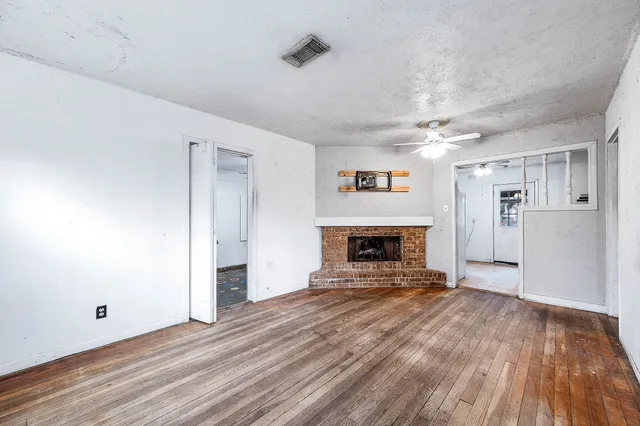 a view of empty room with a fireplace and wooden floor