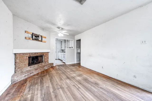 a view of a livingroom with a fireplace a ceiling fan and window
