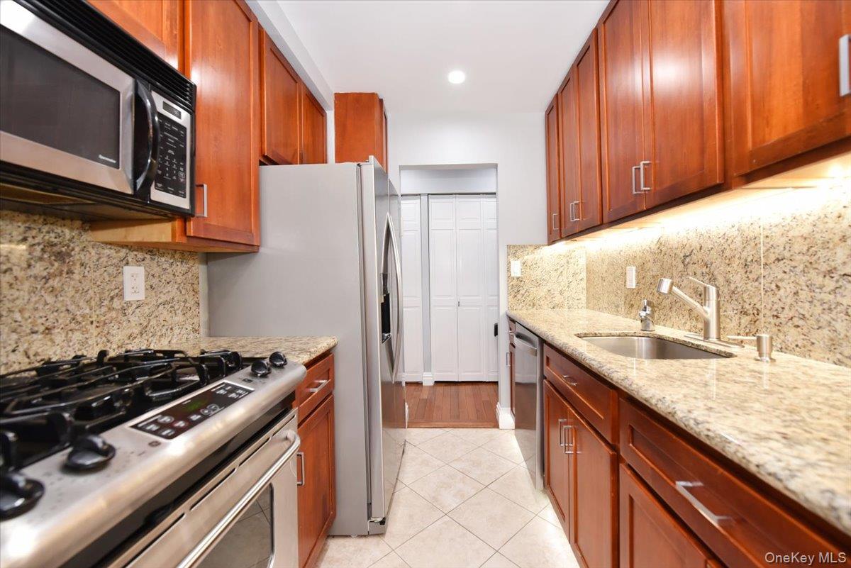 320 East Shore Road, Unit 2A Great Neck, NY 11023 - Photo 20 of 28 a kitchen with granite countertop stainless steel appliances and wooden cabinets