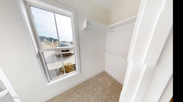 an empty room with a chandelier fan and windows
