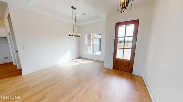 an empty room with wooden floor fireplace and windows