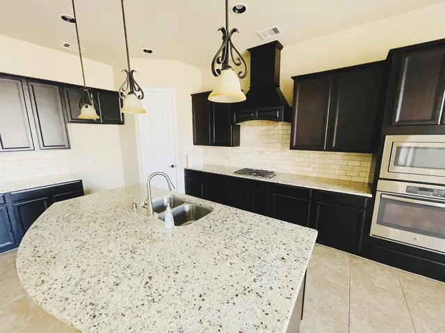 a kitchen with stainless steel appliances kitchen island granite countertop a refrigerator a stove and a sink with wooden floor