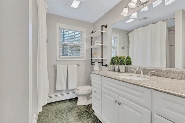 a bathroom with a granite countertop sink mirror vanity and toilet