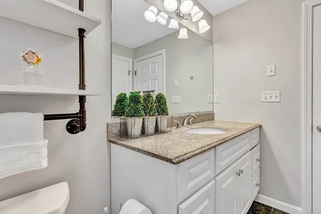 a bathroom with a granite countertop sink a toilet and mirror