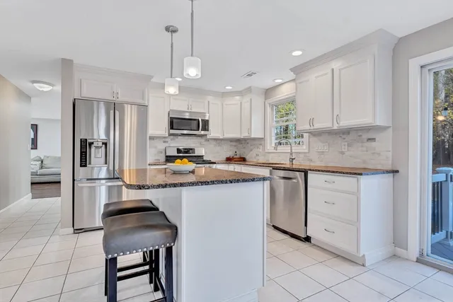 a kitchen with kitchen island granite countertop a stove a sink a refrigerator a counter top space and cabinets