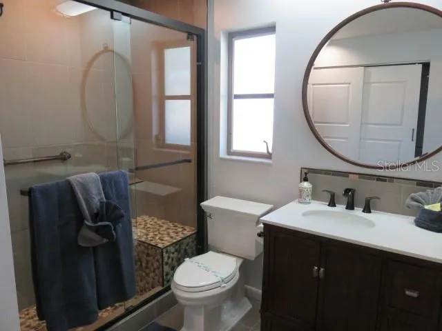 a bathroom with a granite countertop toilet sink and mirror