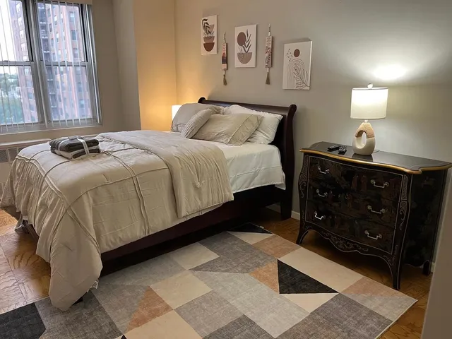 a bedroom with a bed and a lamp on dresser