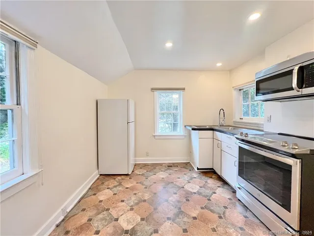 a kitchen with granite countertop a stove a microwave a sink and cabinets