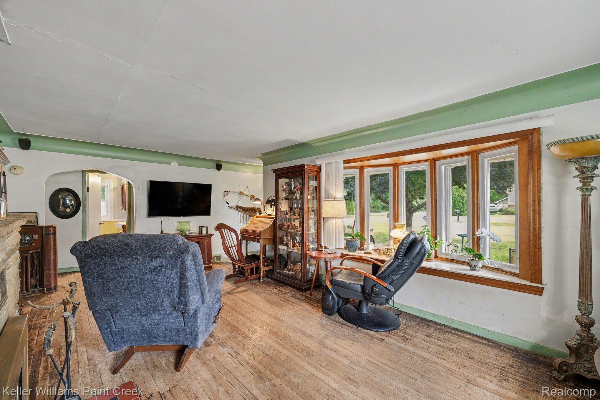 2340 Hessel Avenue Rochester, MI 48307 - Photo 4 of 25 Spacious living area featuring a prominent bay window with wood trim, wood-finish flooring, and an arched entryway