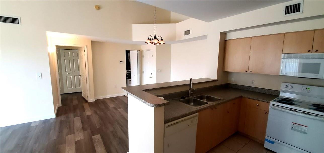 7930 North Nob Hill Road, Unit 3305 Tamarac, FL 33321 - Photo 6 of 28 a kitchen with granite countertop a sink cabinets and wooden floor