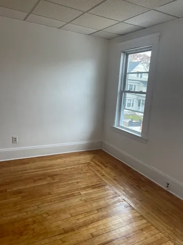 a view of an empty room with closet and wooden floor