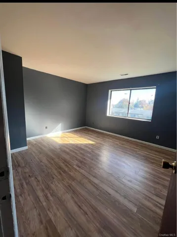 a view of empty room with window and wooden floor