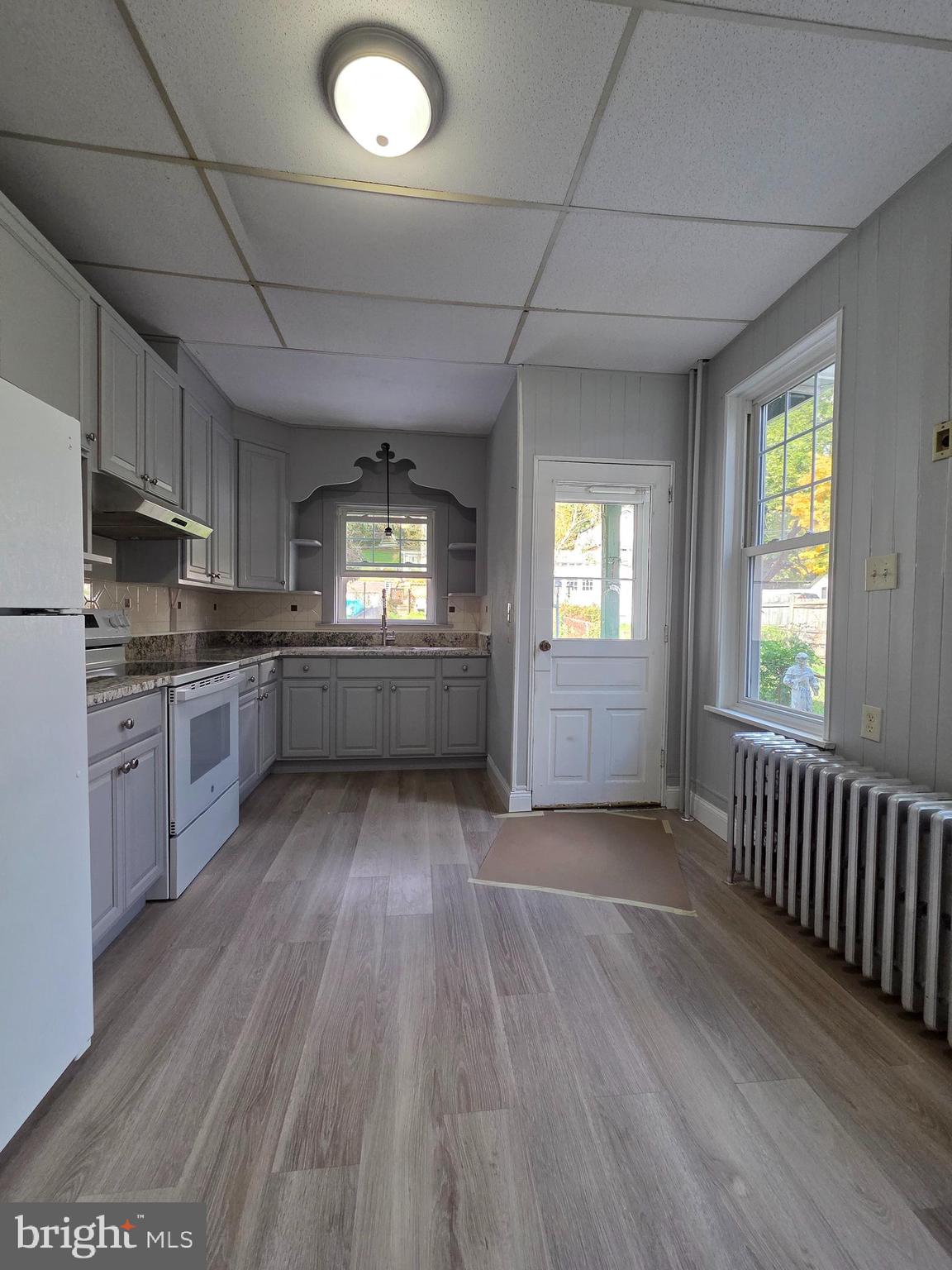 1440 Friedensburg Road Reading, PA 19606 - Photo 11 of 41 a kitchen with granite countertop a stove a sink and white cabinets with wooden floor next to windows