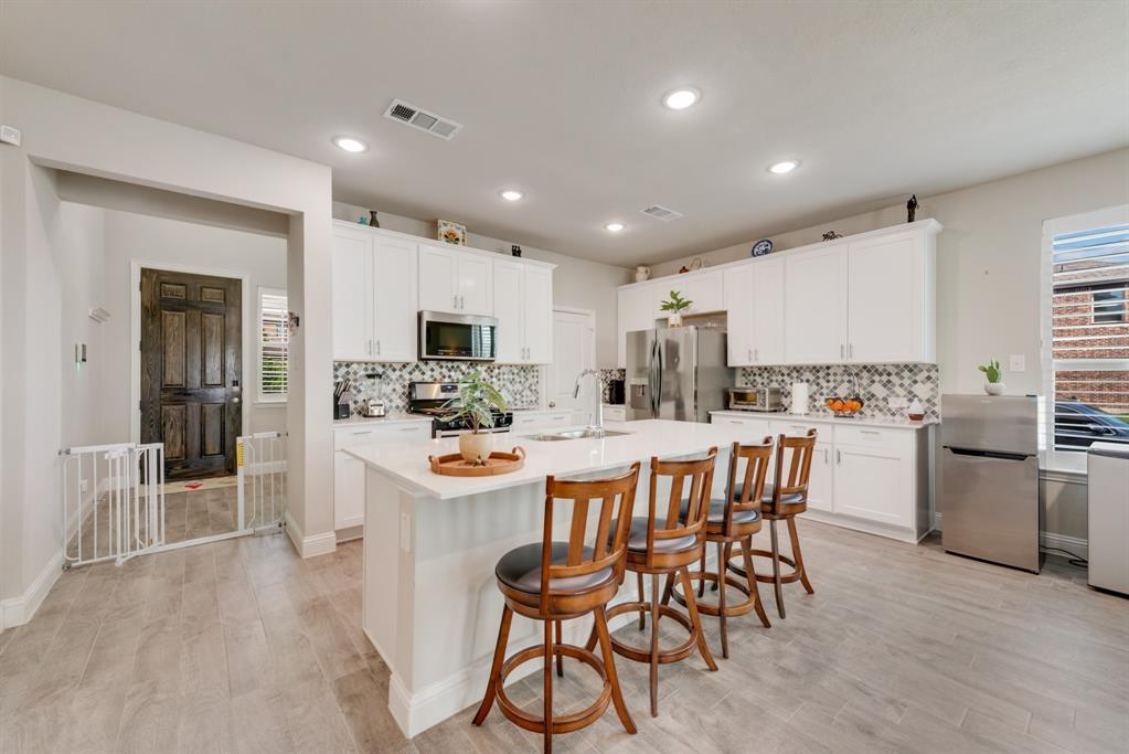 2301 Mount Olive Lane Forney, TX 75126 - Photo 5 of 36 a kitchen with stainless steel appliances kitchen island granite countertop a refrigerator and a stove top oven