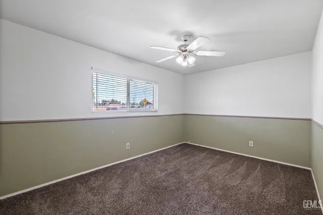 an empty room with a window and ceiling fan