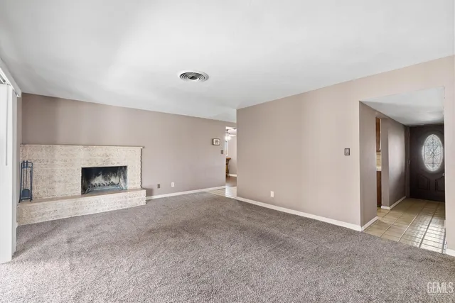 a view of an empty room with a fireplace and a window