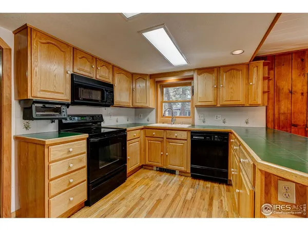 a kitchen with stainless steel appliances kitchen island granite countertop a stove top oven a sink dishwasher a dining table and chairs with wooden floor