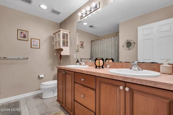 a bathroom with a granite countertop double vanity sink a mirror and a toilet