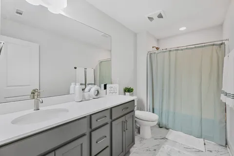 a bathroom with double vanity sinks a toilet a mirror and shower