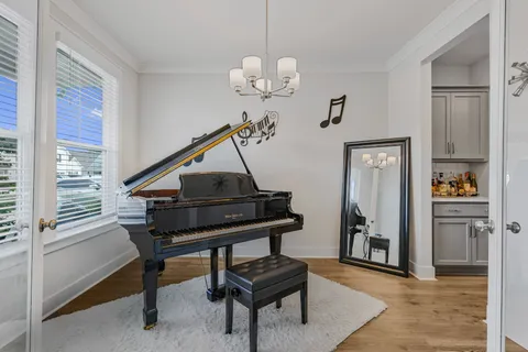 a living room with table a piano and a window