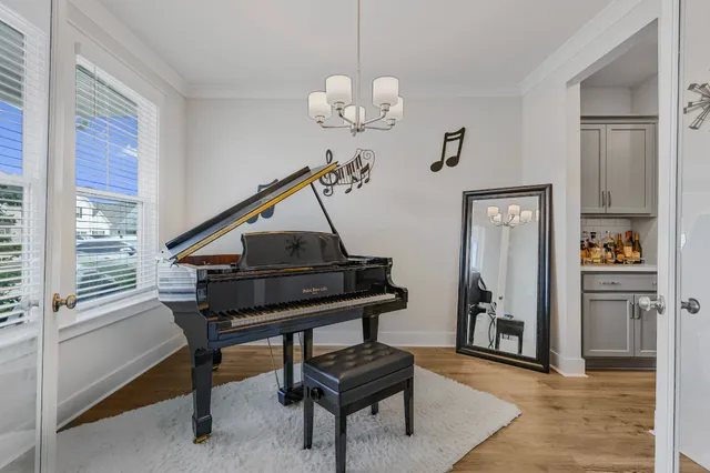 a living room with table a piano and a window