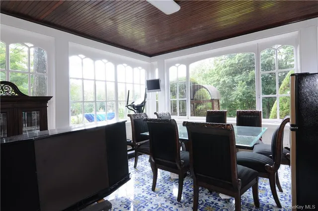 a dining room with furniture a flat screen tv and a floor to ceiling window
