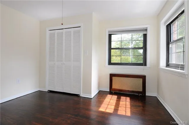an empty room with wooden floor cabinet and windows