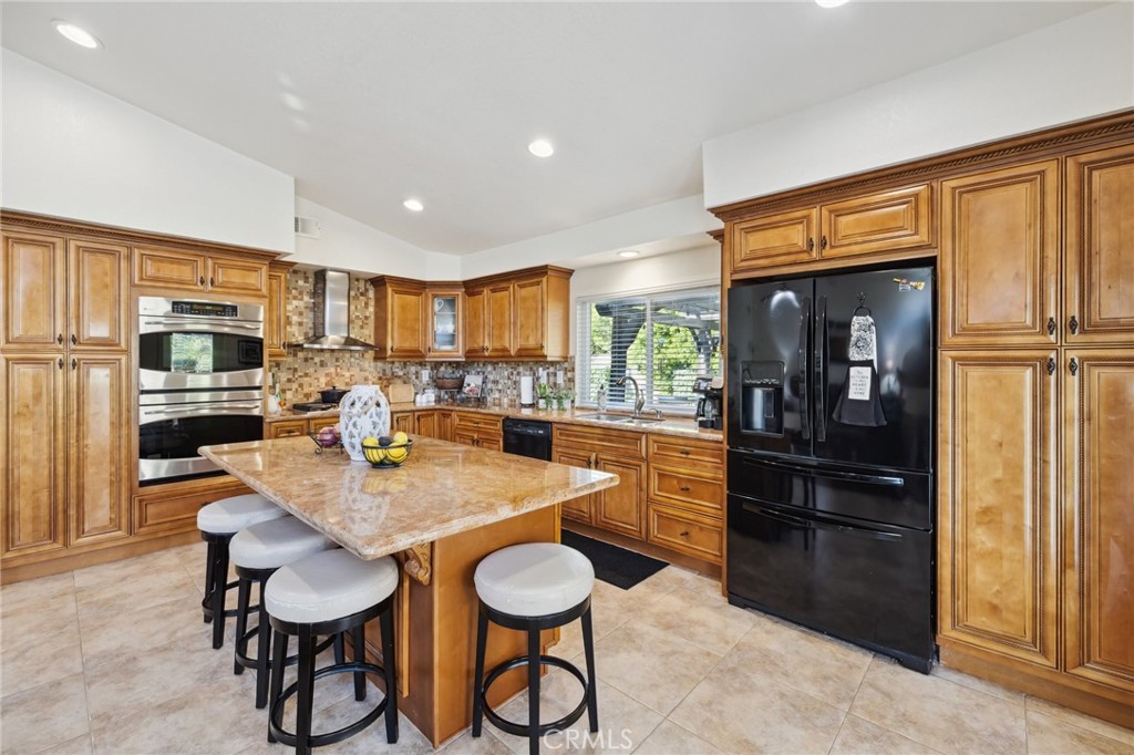 6752 Laurel Brook Drive Riverside, CA 92506 - Photo 18 of 53 a kitchen with stainless steel appliances granite countertop a refrigerator a stove a sink a dining table and chairs