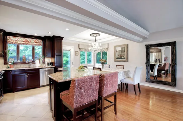 a dining hall with stainless steel appliances granite countertop a stove a sink a dining table and chairs with wooden floor