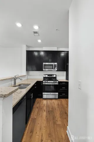 a large kitchen with stainless steel appliances a large counter top a stove and a refrigerator