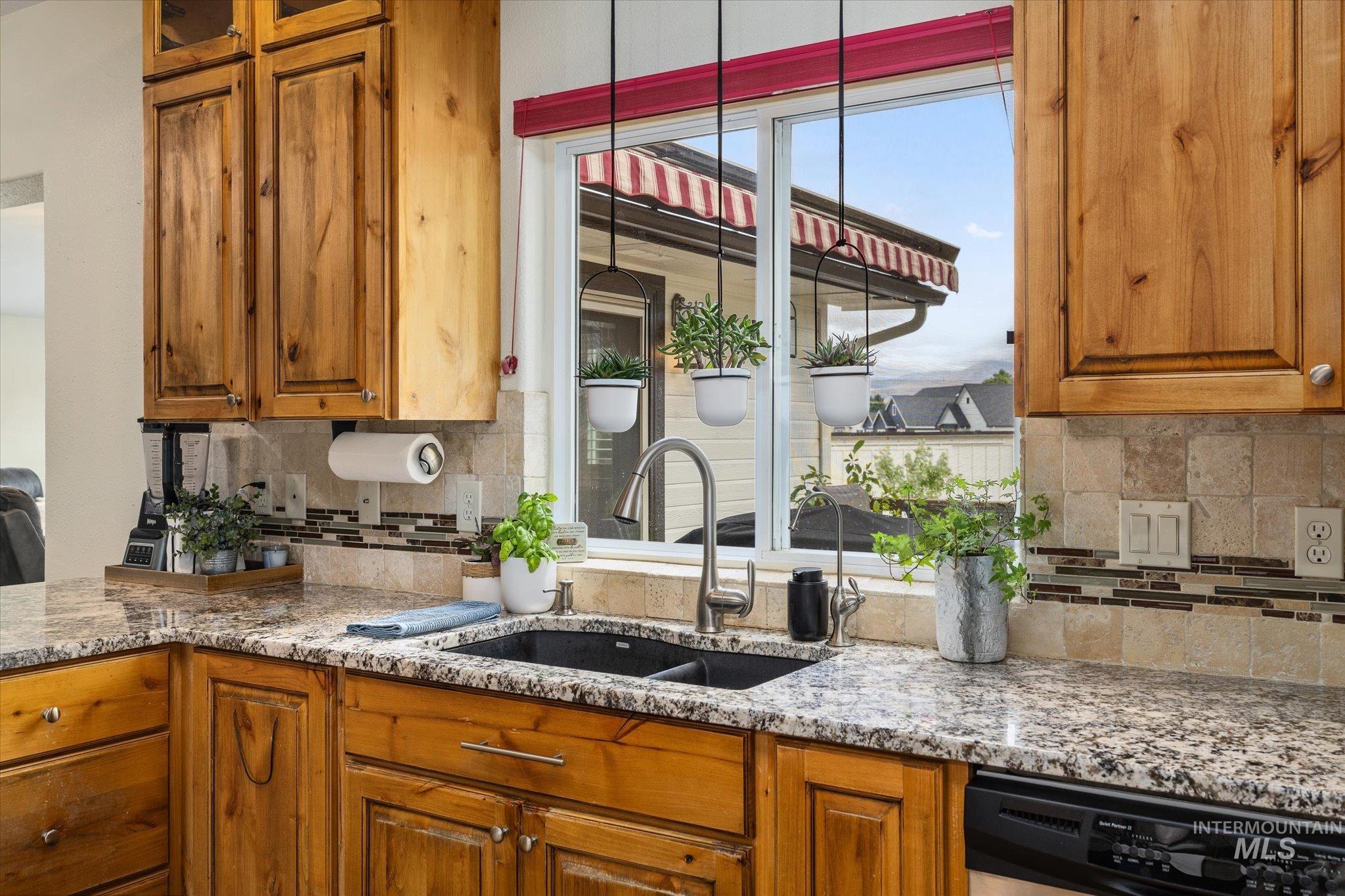 1140 Edgemont Road Emmett, ID 83617 - Photo 7 of 50 Kitchen area featuring wood-finish cabinetry with silver hardware, speckled stone countertops, and a dual-basin sink with a gooseneck faucet