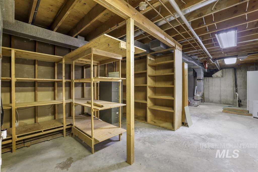 2018 Rancho Vista Drive Twin Falls, ID 83301 - Photo 41 of 50 Unfinished basement space featuring exposed wooden joists, concrete flooring, built-in wooden shelving, and bare concrete walls