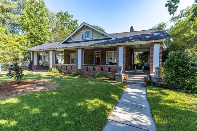 a view of a house with a big yard potted plants and large tree