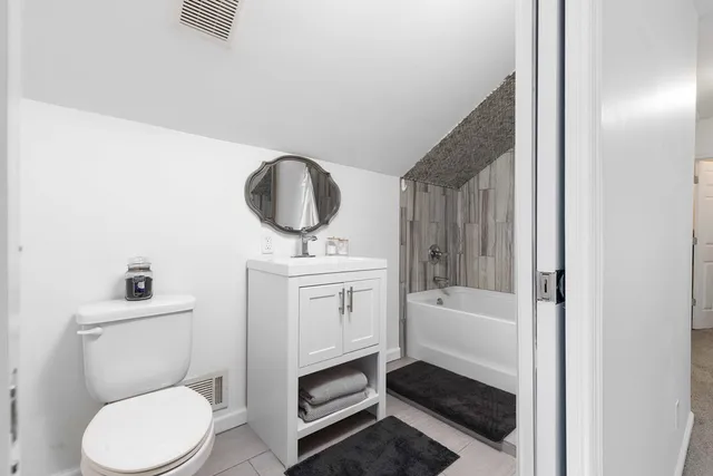 a bathroom with a toilet sink vanity tub and mirror