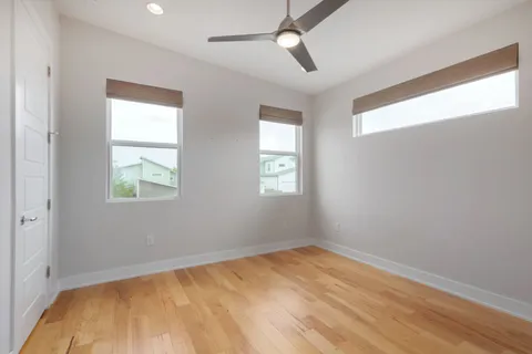 a view of empty room with wooden floor and fan