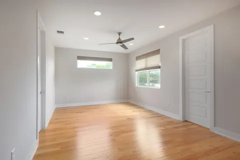 an empty room with windows and ceiling fan