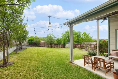 a view of a chairs and backyard with large trees