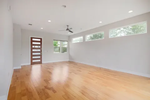 a view of an empty room with a window and wooden floor