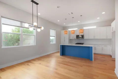 a kitchen with stainless steel appliances kitchen island granite countertop a refrigerator a sink dishwasher a stove and white countertops with wooden floor