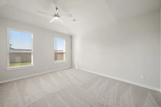 an empty room with windows and ceiling fan