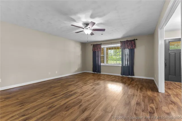 a view of an empty room with window and wooden floor