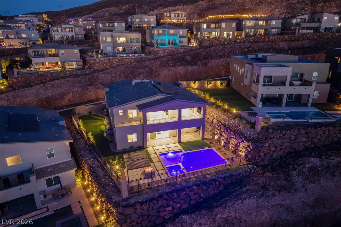 526 Riley Ridge Henderson, NV 89012 - Photo 4 of 10 An aerial perspective reveals multiple properties with pools and manicured landscaping, all illuminated under the evening sky.